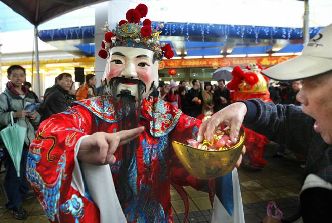 圖為1位民眾拿取財(cái)神爺發(fā)放的金元寶喜糖以沾財(cái)運(yùn)。(圖/《中時(shí)電子報(bào)》 王錦河攝) 圖為1位民眾拿取財(cái)神爺發(fā)放的金元寶喜糖以沾財(cái)運(yùn)。(圖/《中時(shí)電子報(bào)》 王錦河攝)
